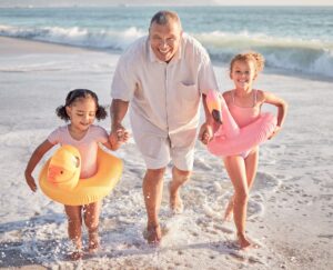 grandfather and children playin on beach